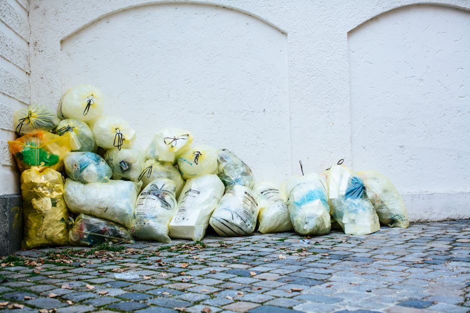 A rectangular white sign with black uppercase text reading 'NO DUMPING OF RUBBISH' is mounted on a red brick wall. The wall features a pattern of horizontal bricks with varying shades of reddish-brown